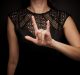 Against a black background, we see a woman wearing a black dress as she signs LOVE.